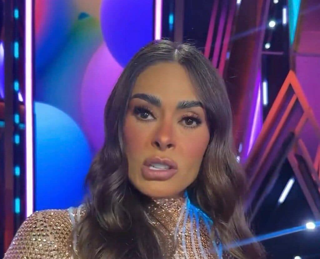 Galilea Montijo con un vestido brillante y expresión seria, en un escenario iluminado, enfrentando críticas por su cambio de imagen.