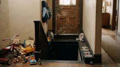 Escalera de una guardería con juguetes esparcidos y un acceso al sótano donde se encontraron 12 niños hacinados en un automóvil.