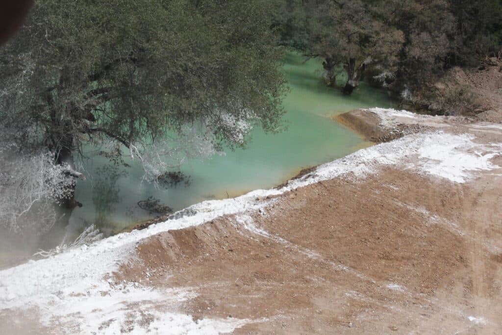 Contaminación visible en el Río Sonora, con aguas de color verde y sedimentos blancos, reflejando el impacto del derrame de Grupo México.