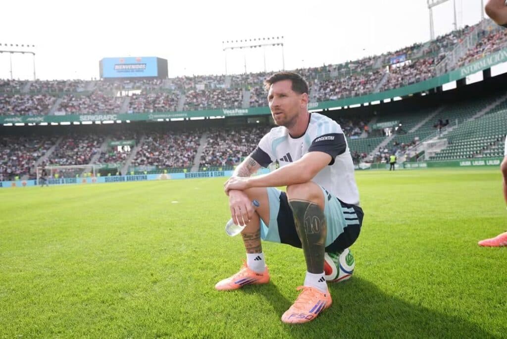 Lionel Messi sentado en el campo de juego, con la camiseta de la Selección Argentina, durante un partido de despedida.